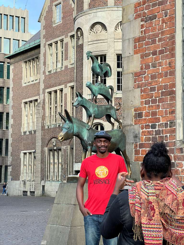 Mann posiert mit den Bremer Stadtmusikanten und Frau macht Foto